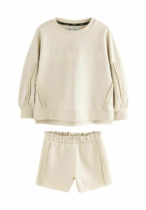 Beige tröja och shorts-set med avslappnad passform. Tröjan har rund halsringning och lätt puffärmar; shortsen har ett elastiskt midjeband.