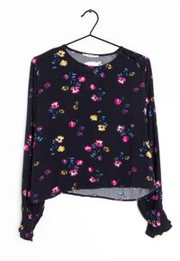 Langærmet marineblå bluse i blødt stof, med levende blomsterprints i pink, lilla, gul og blå, samt rynkede mansjetter og en rund kant.