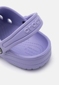 Sandal Crocs roxo com uma única alça ajustável, base texturizada e design perfurado para respirabilidade. Material leve.