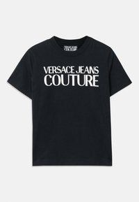 Juodas medvilninis marškinėliai su trumpomis rankovėmis, kuriuose dideliu baltu tekstu parašyta "VERSACE JEANS COUTURE" per krūtinę.