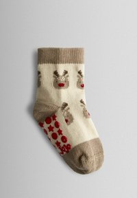 Calcetines crema hasta la rodilla con puño acanalado marrón, con un patrón de renos y detalles antideslizantes en rojo en forma de puntos y estrellas en la suela.