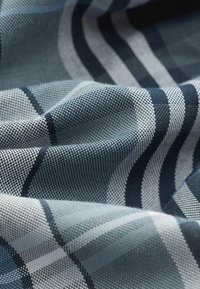 Geweven stof met afwisselende strepen in blauw, marineblauw en lichtgrijs. De textuur toont een subtiel ruitenpatroon en een gladde afwerking.