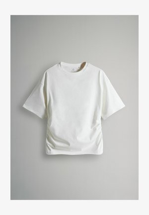 Vit bomullströja med korta ärmar, rund halsringning och droppad sidodetalj för en figursydd form. Slät textur, minimalistisk design.
