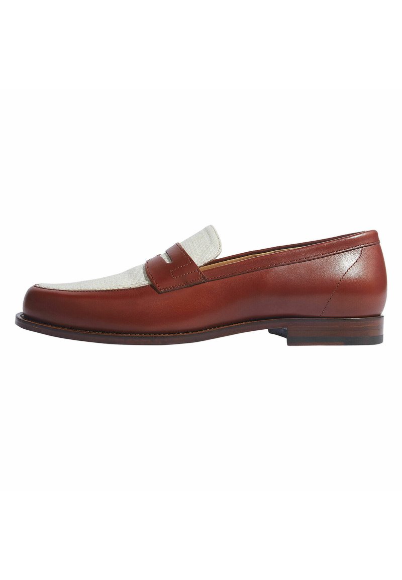 Bruine leren loafers met een geweven roomkleurige bovenkant, platte hak en subtiele stikdetails langs de randen.