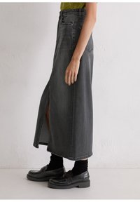 Grijze denim maxi rok met een split aan de voorkant, met een hoge taille en een rechte silhouet. Gelaagd met zwarte loafers en ribbel sokken.
