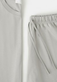 T-shirt en coton gris clair et short assorti à taille élastique avec cordons, posés côte à côte sur une surface blanche.