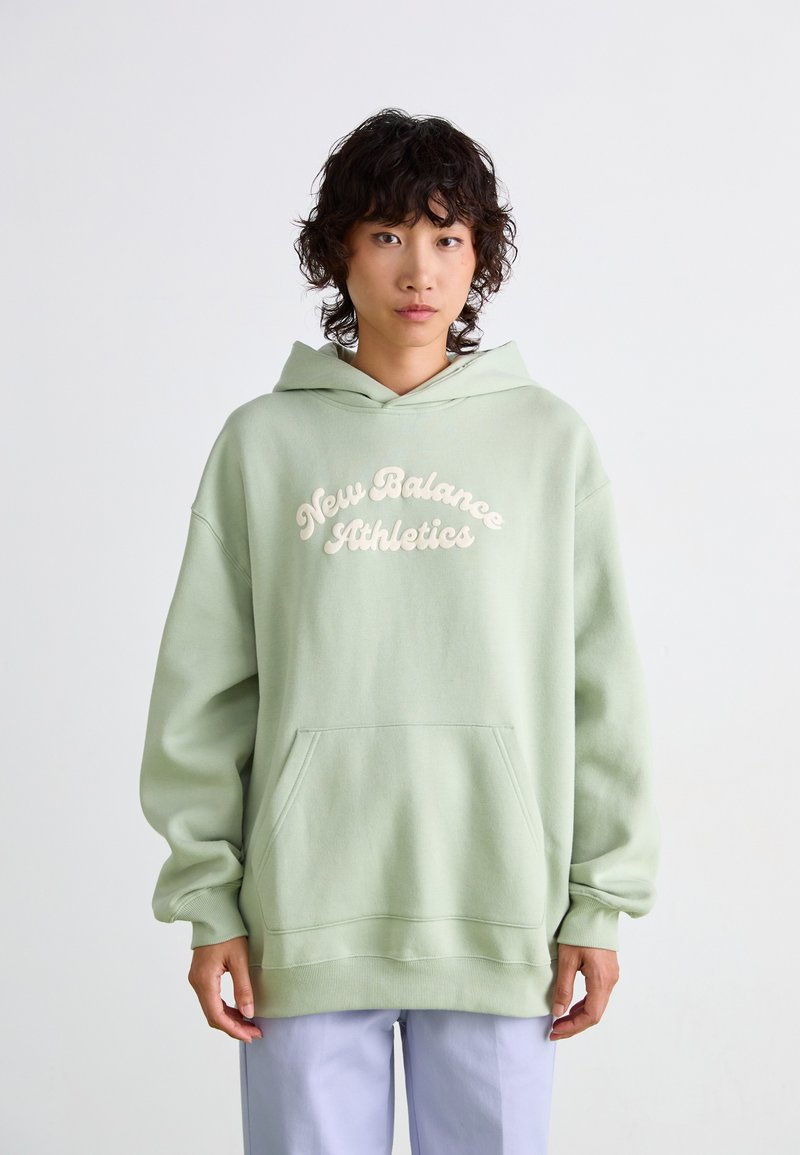Hoodie verde chiaro realizzato in morbido tessuto, con la scritta "New Balance Athletics" in crema. Presenta una tasca frontale e una vestibilità rilassata.