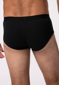 Zwarte katoenen boxershorts met een gladde textuur en een elastische tailleband waarop de merknaam "JP1880" in een subtiele, bijpassende print is afgebeeld.