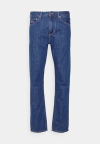 Tmavě modré džínové kalhoty s rovnými nohavicemi. Mají pět kapes, měděné kovové doplňky a jemné vyblednutí látky.