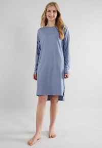 Camicia da notte a maniche lunghe in cotone azzurro chiaro con scollatura rotonda, dotata di un piccolo logo al centro e spacchi laterali all'orlo.