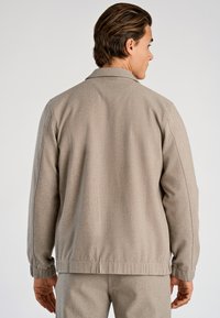 Szara teksturowana kurtka o luźnym kroju, z kołnierzem do złożenia, długimi rękawami oraz elastycznymi mankietami i dołem dla komfortu.