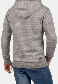 Sudadera con capucha a rayas grises vista desde atrás, con capucha ajustable con cordón, puños acanalados y una etiqueta de cuero en el dobladillo.