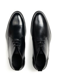 Scarpe in pelle nera con finitura liscia, punta arrotondata e design con lacci. Presentano cuciture minime e una linguetta laterale per facilitare la calzata.