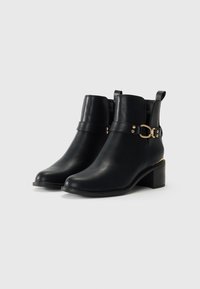 Black leather ankle boots with a smooth finish, featuring a strap with a gold-tone buckle and a low block heel.