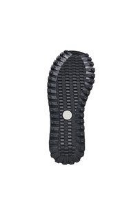 Black rubber shoe sole with textured tread, featuring circular dots and a central logo. Distinct ridges for enhanced grip and support.