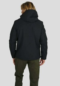 Veste à capuche noire avec un extérieur lisse, dotée d'un col haut et de longues manches, portée sur un pantalon vert olive. Design simple et fonctionnel.