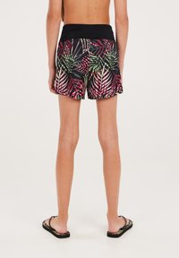 Zwarte bikini shorts met een levendig groen en roze palmbladerenpatroon, voorzien van een brede zwarte tailleband en een gladde stofstructuur.