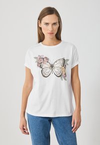 Hvid bomulds t-shirt med et stort sommerfugl grafik, accentueret med rosa og gule blomsterdesigns på hver side. Korte oprullede ærmer.
