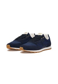Sneaker blu navy con tomaia in suede e tessuto, dotate di una zeppa bianca, suola in gomma naturale e lacci neri. Logo dorato sulla linguetta.