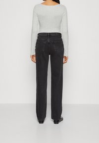 Jeans de mezclilla negra con un diseño de pierna recta, cinco bolsillos y una cintura de altura media. La tela tiene una textura suave con sutiles detalles de costura.