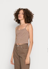 Top cropped em padrão xadrez castanho e branco, com alças finas e detalhes franzidos, combinado com calças castanhas de cintura alta. Textura de tecido suave.