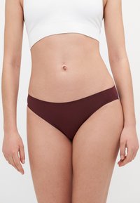Chilot de baie maron, confecționat dintr-un material neted, având o croială joasă și un design minimalist, cu un detaliu mic al logo-ului pe lateral.