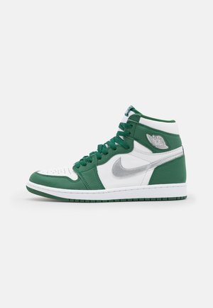 Baskets hautes en cuir blanc et vert avec un swoosh Nike argent métallisé et le logo Air Jordan sur le col de la cheville.