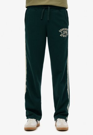 Pantalones de chándal verdes oscuros con cintura ajustable, rayas cremosas a los lados y la impresión "Superdry JPN Athletic" en la parte frontal. Tela suave y cómoda.