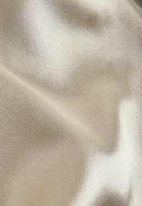 Satin fabric in a soft beige hue with a smooth, shiny texture, displaying subtle light reflections and a fine weave pattern.