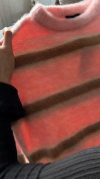 Pull rayé rose et crème avec un col rond côtelé et une texture douce ; comporte des rayures horizontales marron sur le corps.