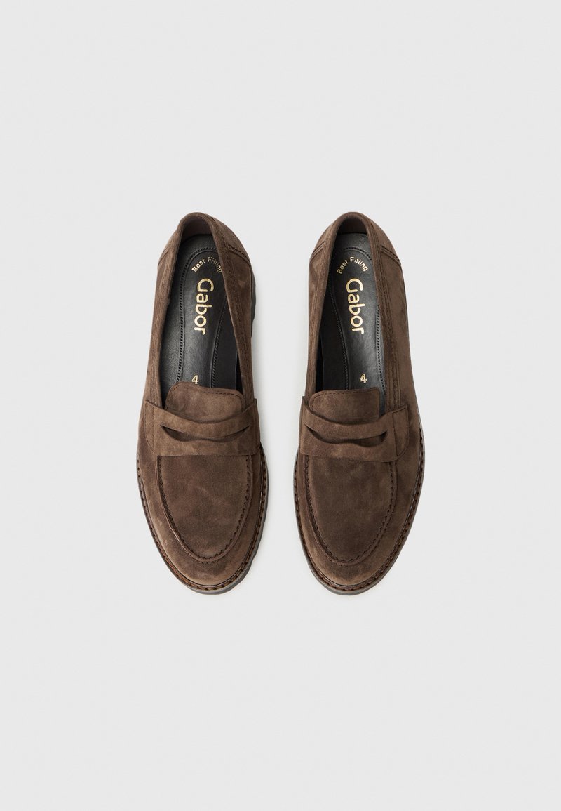 Ein Paar braune Wildleder-Loafers mit gesticktem Mokassin-Zehen und Riemen-Details, etikettiert Gabor, von oben auf einem hellgrauen Hintergrund dargestellt.
