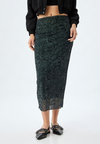 Zijdeachtige zwarte en groene midi-rok met een tijgerprintpatroon, voorzien van een aansluitende tailleband en een rechte snit, gecombineerd met zwarte schoenen.
