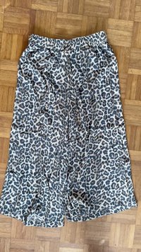 Leopard print shorts made of light fabric, featuring an elastic waistband with a drawstring and a loose fit, displayed on a wooden floor.