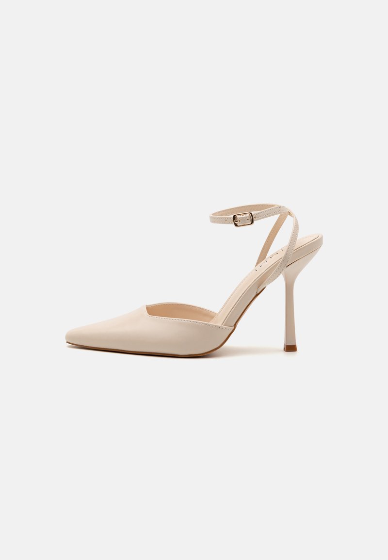 Escarpins en cuir verni beige avec un bout pointu, une fine bride de cheville et un talon aiguille de 10 cm ; design minimaliste et texture lisse.