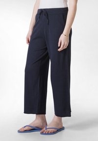 Navyblauwe wijde broek met een trekkoord in de taille, gemaakt van zachte stof; kenmerken zijn onder andere zijzakken en een ontspannen pasvorm.