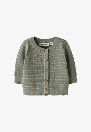 Grønn strikket cardigan med et teksturert mønster, treknapper og rund hals. Korte ermer med en etikett på kanten.