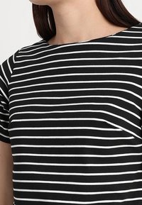 Czarny i biały pasiany T-shirt z okrągłym dekoltem i krótkimi rękawami, wykonany z miękkiego materiału, z równomiernie rozmieszczonymi poziomymi paskami.