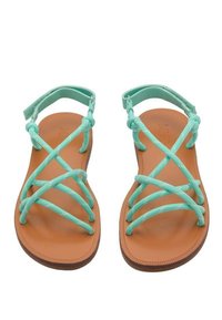 Turkosa sandaletter med remmar och en platt brun gummisula, med korslagda remmar och en bakre ankelsnodd för stöd.