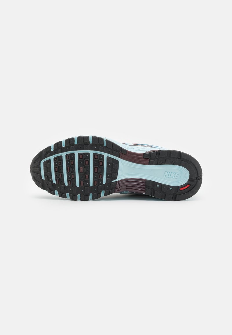 Semelle de chaussure de sport Nike avec un design flexible en caoutchouc noir, doté de motifs de traction prononcés, rehaussée d'éléments bleu clair et bordeaux foncé.