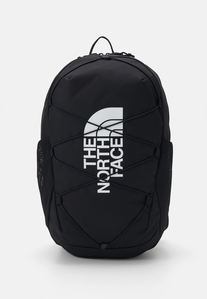 Black backpack with a rounded shape, featuring elastic webbing across the front, mesh side pockets, and a prominent white logo.