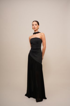 Black evening gown featuring a strapless, fitted bodice with a high neck and asymmetrical draped skirt. Material: smooth fabric with a sheer overlay.