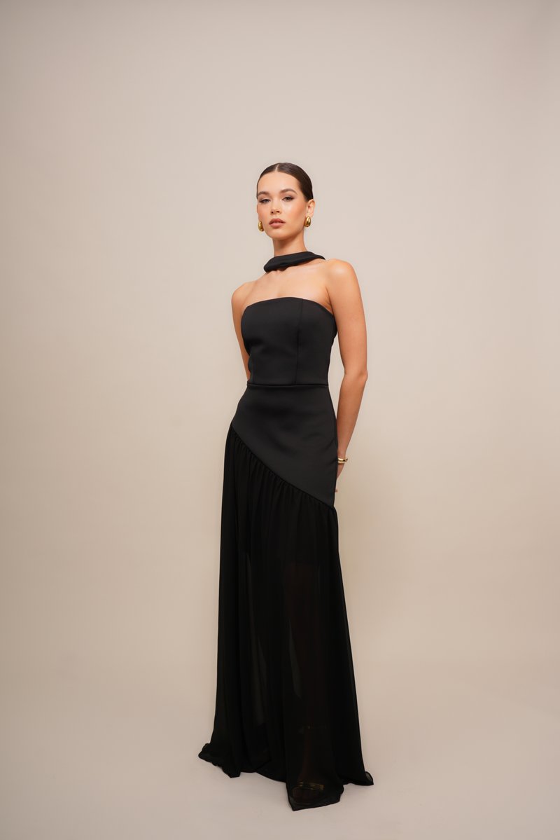 Black evening gown featuring a strapless, fitted bodice with a high neck and asymmetrical draped skirt. Material: smooth fabric with a sheer overlay.