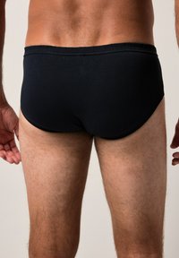 Černé plavecké šortky vyrobené z hladkého materiálu, s flexibilním pasem. Design zahrnuje jednoduchý, klasický střih, který poskytuje minimální zakrytí.