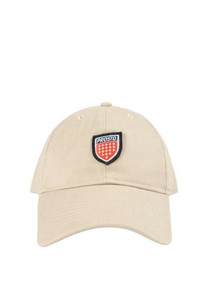 Beżowa czapka bejsbolowa z zakrzywionym daszkiem i naszywką w kształcie tarczy z napisem „PROSTO” nad czerwonymi i białymi symbolami krzyża.