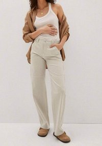 Bežové pruhované kalhoty s vysokým pasem, rovnými nohavicemi a bočními kapsami, doplněné bílým topem a hnědou košilí.