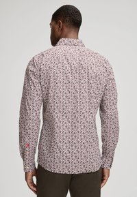 Langarmshirt met een witte stof en een klein bordeauxrood bloemenpatroon. Inclusief knoopmanchetten en een standaard kraag.