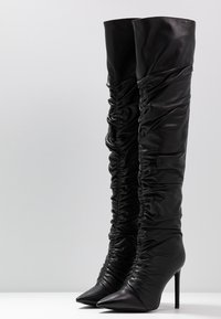 Schwarze, hohe Stiefel aus weichem Leder mit geraffter Textur, spitzem Absatz und Stiletto-Absatz. Schlankes Design reicht über das Knie.