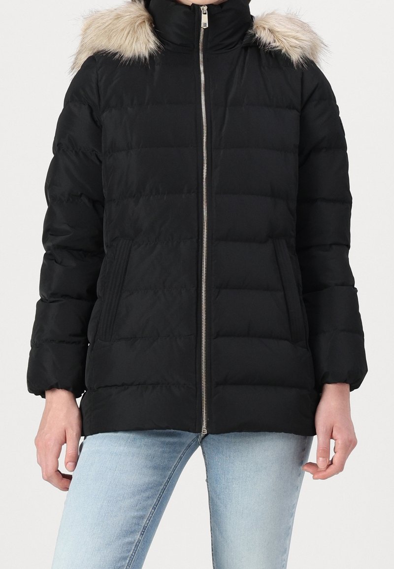 Zwarte donsjas met ritssluiting, capuchon met bontvoering, geribbelde mouwboorden en twee steekzakken aan de voorkant. Gewatteerd ontwerp met een lichtgewicht textuur.