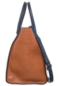 Bolso de mano de cuero marrón con asas azules y correa de hombro ajustable, mostrado de lado sobre un fondo blanco.