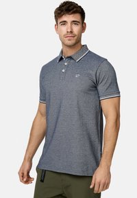 Marineblauwe poloshirt met kraag, voorzien van een contrasterende bies, drie-knopen sluiting en geborduurd logo op de borst. Zachte stof.
